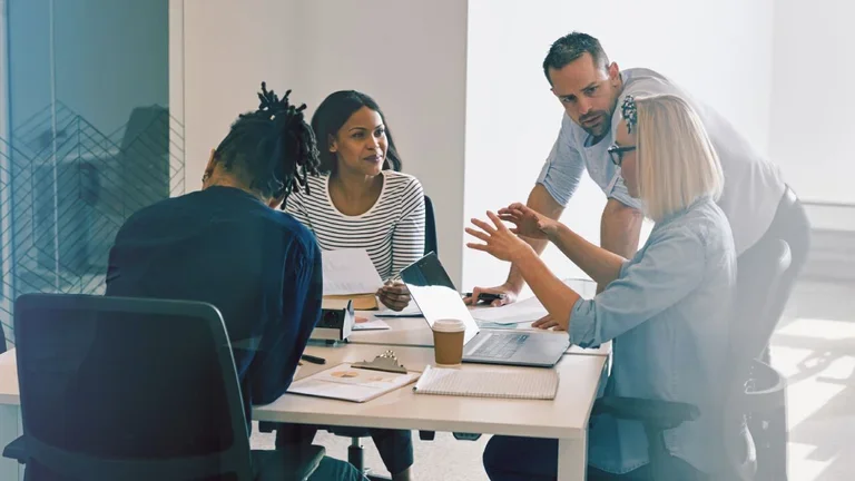 C-Suite members sat around a table speaking and solving problems together